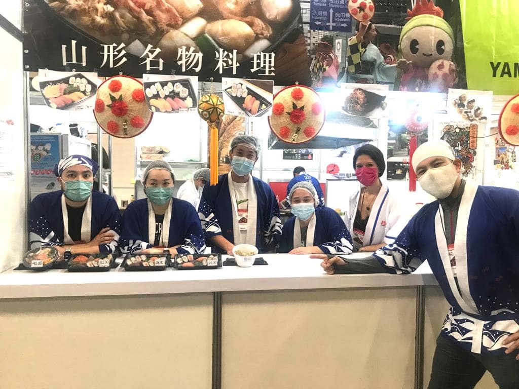 Equipe de voluntários posando com bandejas de sushi no Festival do Japão de 2022