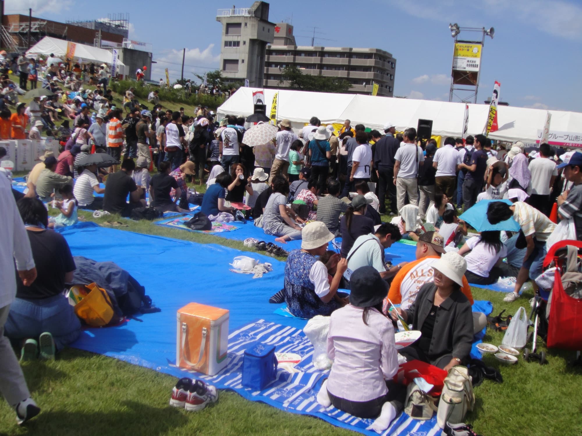Grupo reunido sobre uma lona azul no festival do imoni