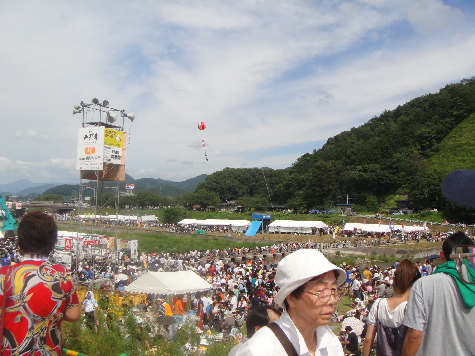 Multidão reunida no festival do imoni em Yamagata, com guindaste ao fundo